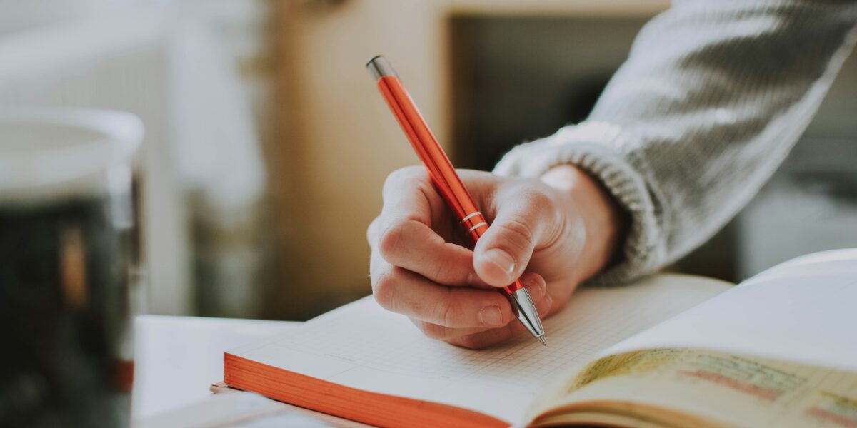 Person writing in a notebook to work through a decision